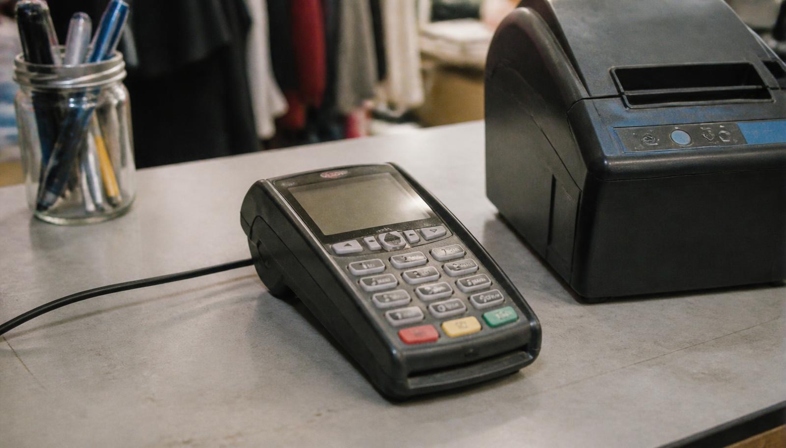 Small business owner processing a payment on a credit card machine at checkout counter