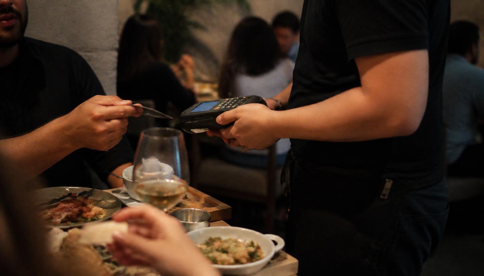 Server using a handheld POS terminal to take a restaurant order tableside