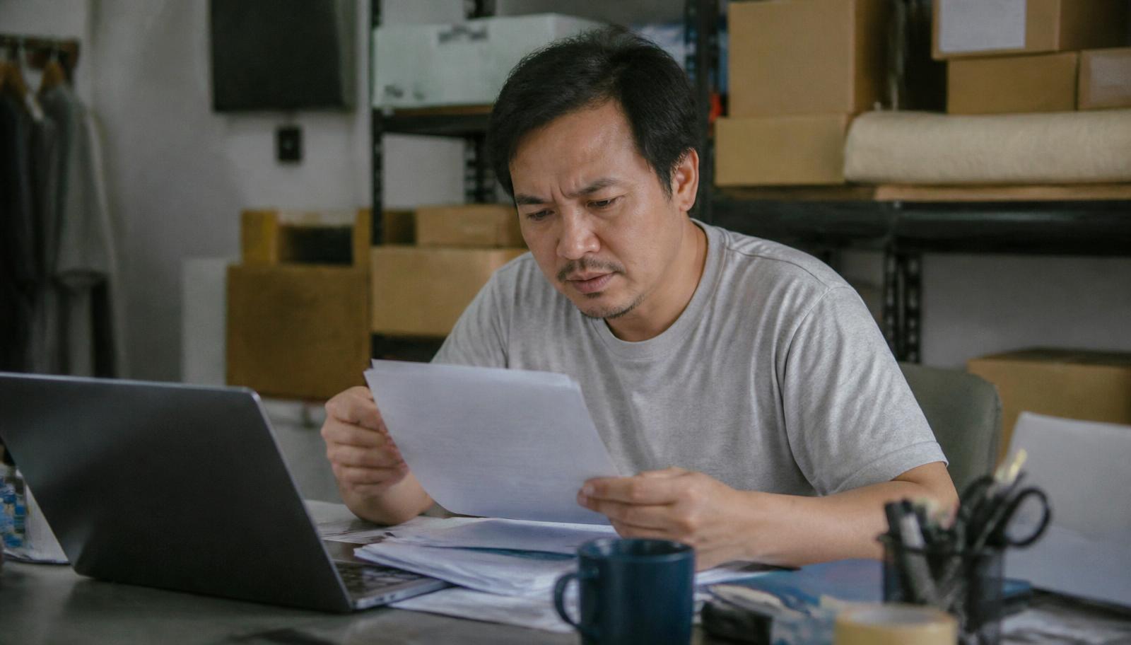 Business owner reviewing high-risk merchant account paperwork and underwriting documents