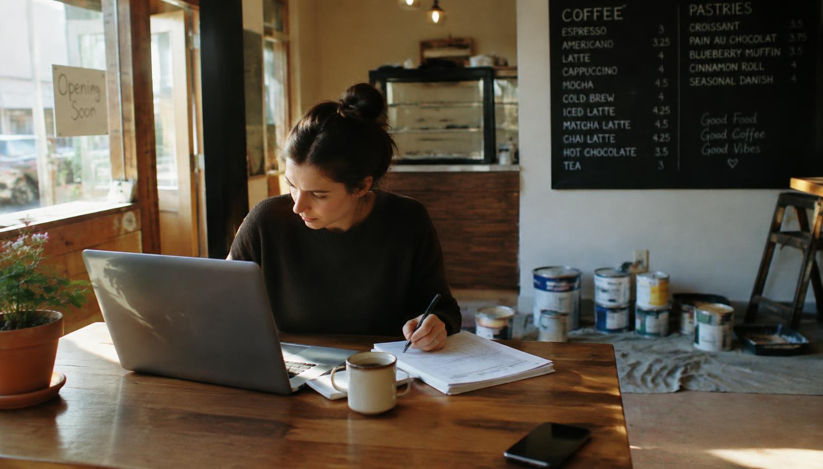 Small business owner filling out a merchant account application on a laptop next to a stack of paperwork